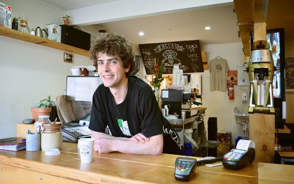 Smiling young man leaning on the cafe counter