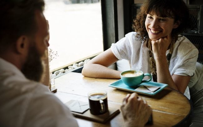 Happy couple sitting by the table enjoying coffee