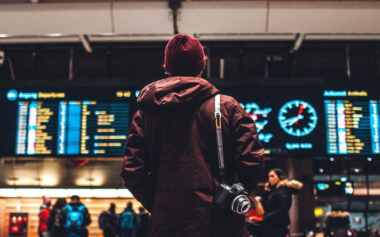 Man standing in front of the departures board at an airport